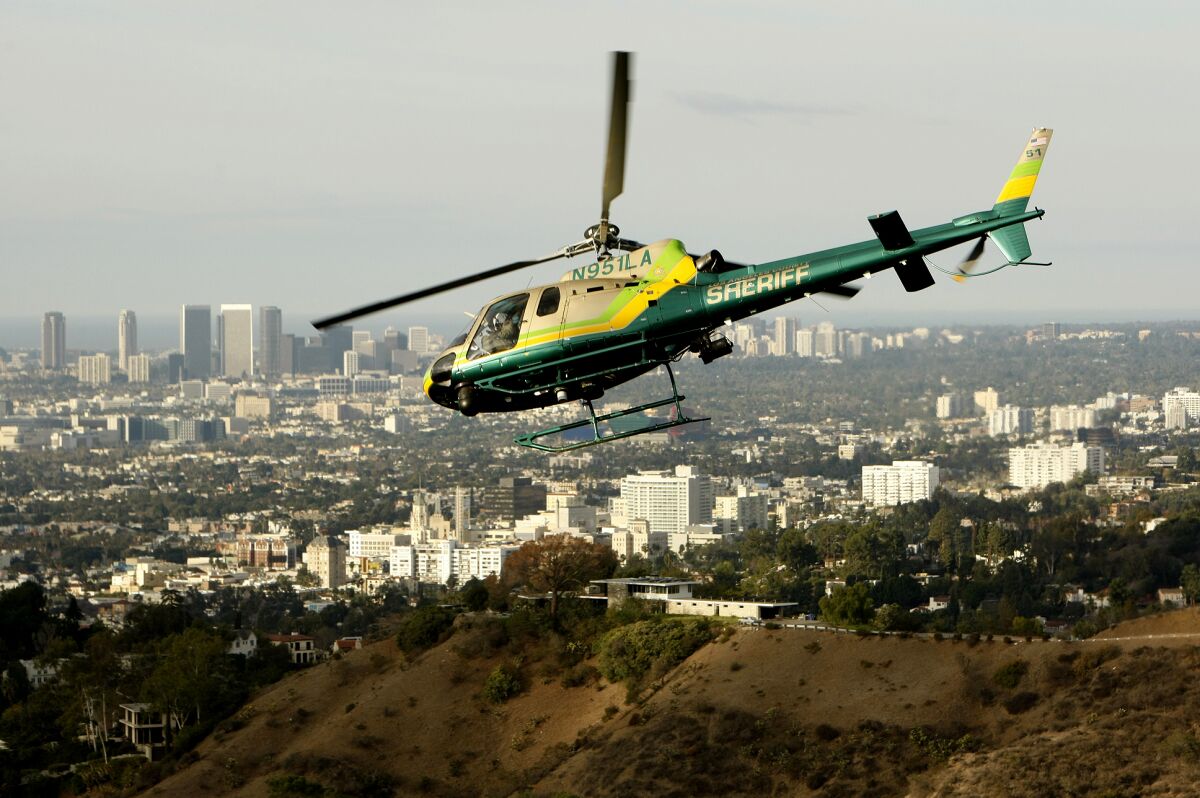 A helicopter with "sheriff" on the tail flies above a city.