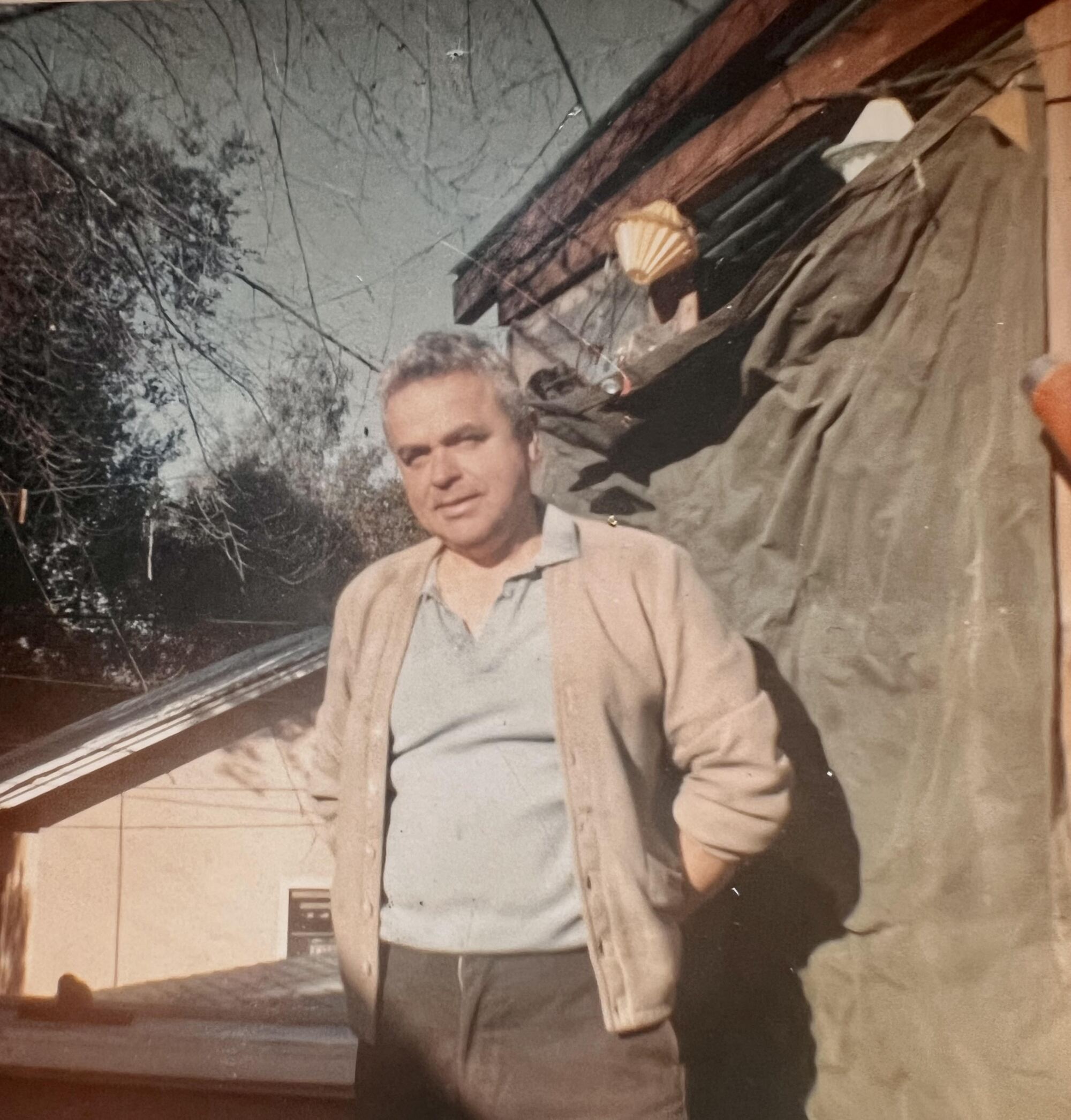 An old photo of Richard Bartindale wearing a blue shirt and a tan sweater, taken outdoors.