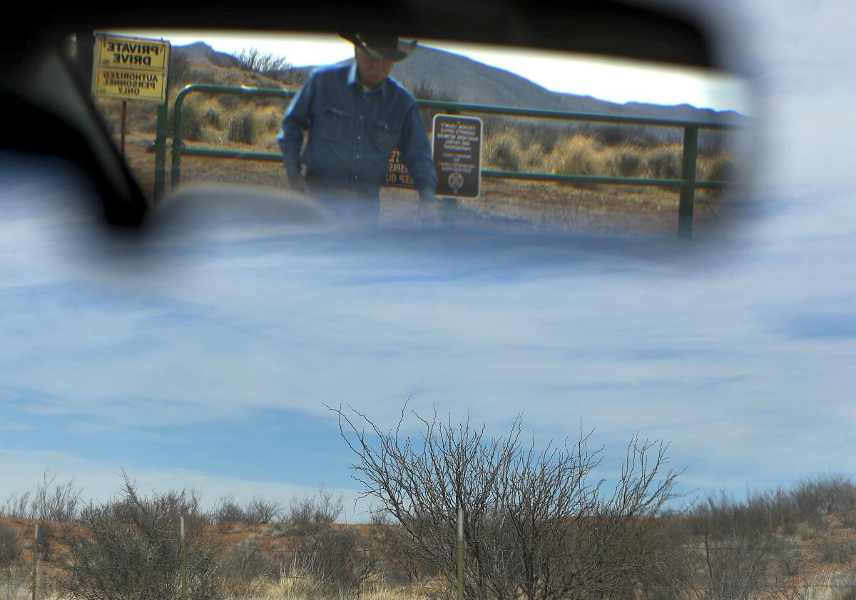 Rancher John Ladd is reflected in a mirror as he checks on cattle at his ranch on the southern Arizona border.