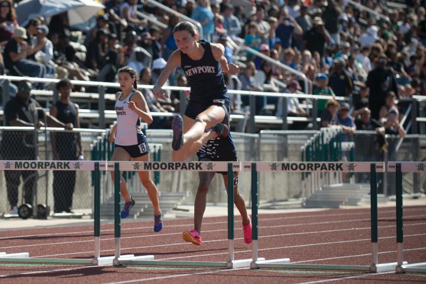 Newport Harbor's Natalie McCarty leaps into the home stretch of the 300-meter hurdles.