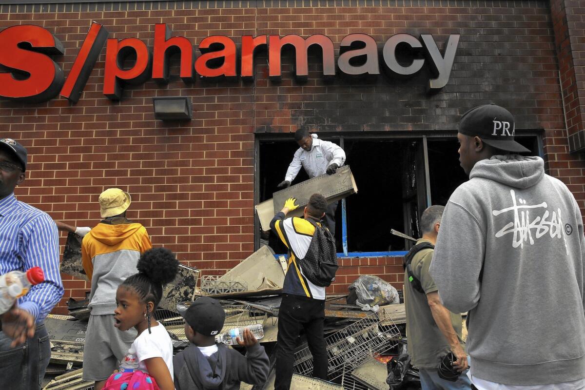 Volunteers clean up a CVS drugstore in Baltimore that was looted and burned Monday night.