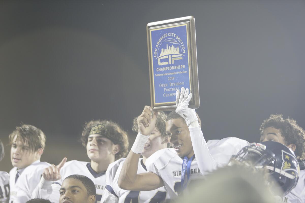 Mason White (19) lifts the winning plaque as Birmingham celebrates after the 2019 City Section Open Division title game.
