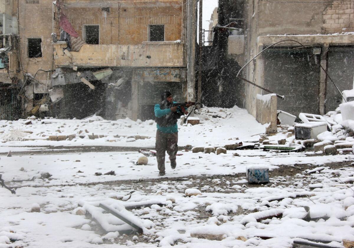 A Syrian rebel aims his weapon as he stands amid snow during clashes with pro-government forces in the Salaheddin neighborhood of Aleppo.