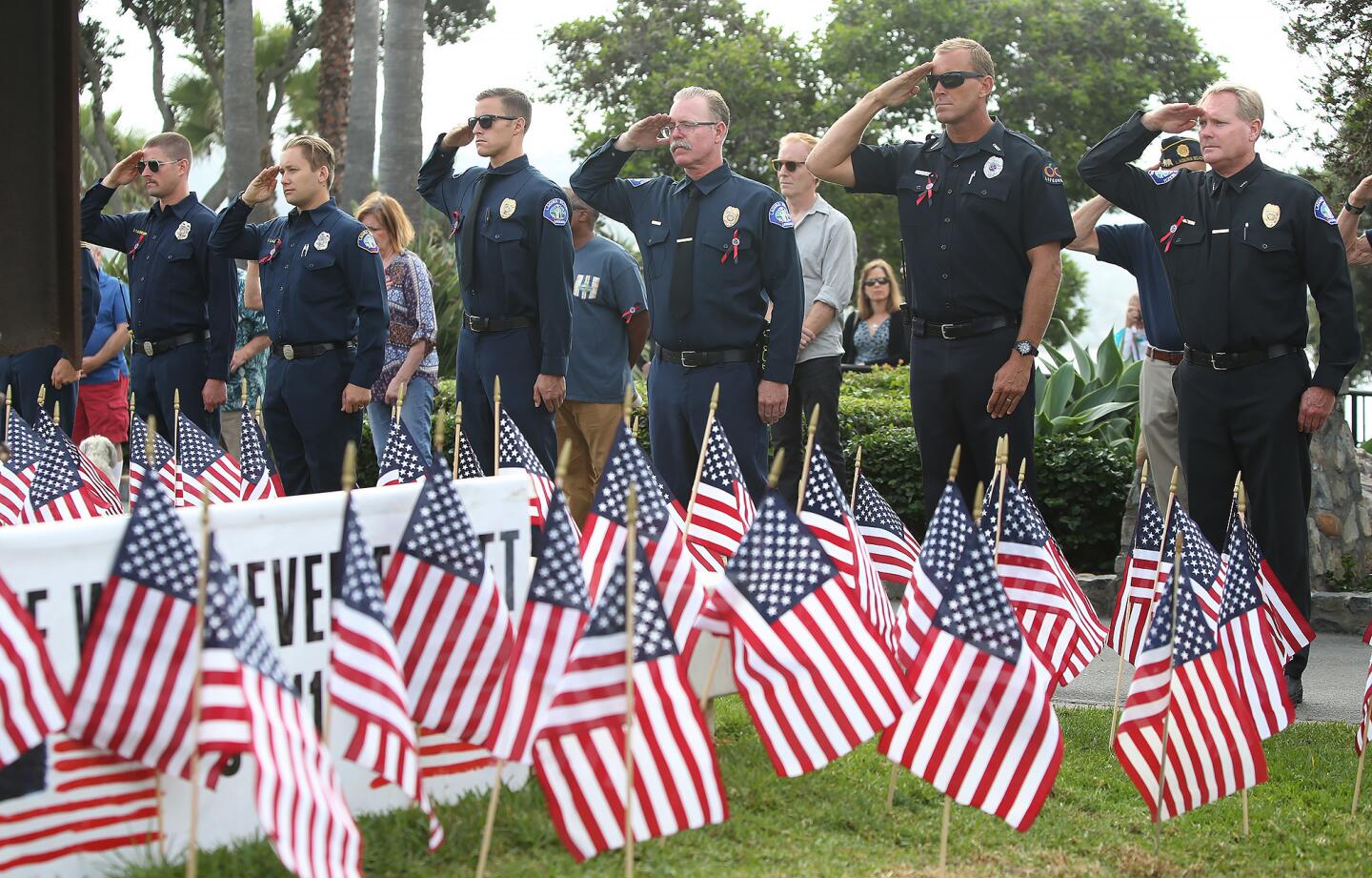 Members of the Laguna Beach fire and marine safety departments salute as bells ring during a 9/11 ceremony of remembrance Tuesday morning at Monument Point in Heisler Park.