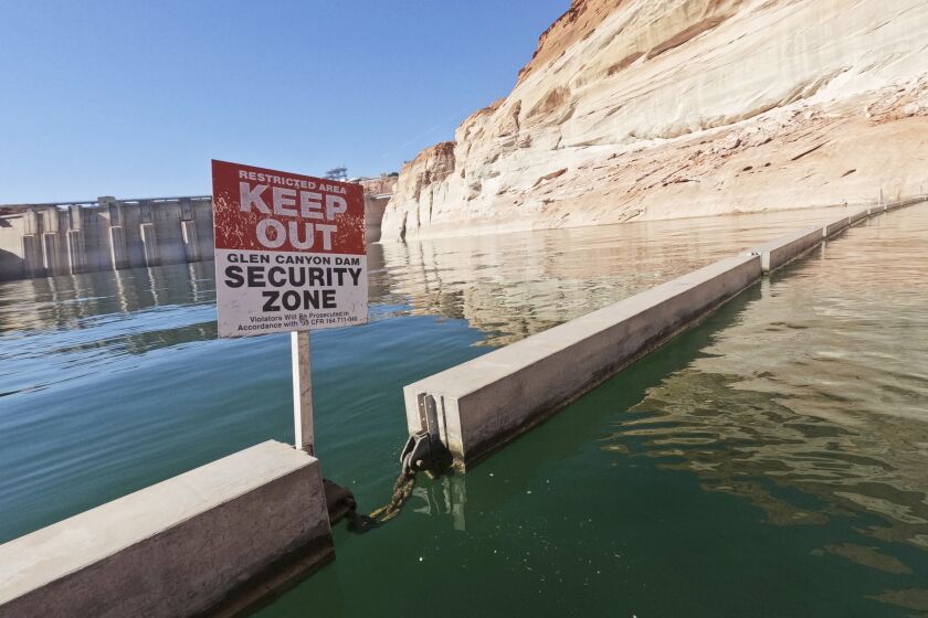 FILE - A sign reading "keep out" is displayed just upstream of Glen Canyon Dam at Lake Powell, June 8, 2022, in Page, Ariz. As America's large reservoirs on the Colorado River drop to record-low levels, fish are among those suffering the impact. (AP Photo/Brittany Peterson, File)