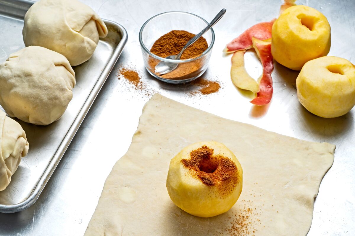 The peeled and cored apples are sprinkled with cinnamon and sugar before being wrapped.