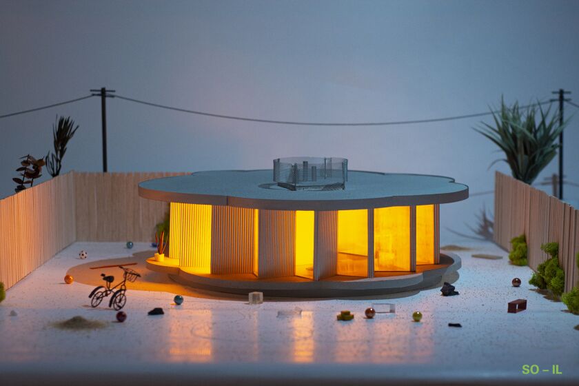 A photograph of a model shows a rounded structure with a saw tooth facade illuminated from within.