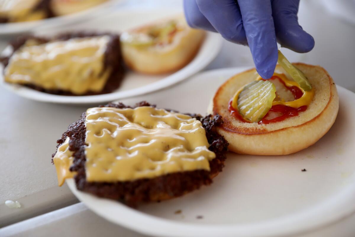 The Smash Burger is dressed simply with sour pickles, minced white onion and a squirt each of ketchup and mustard.