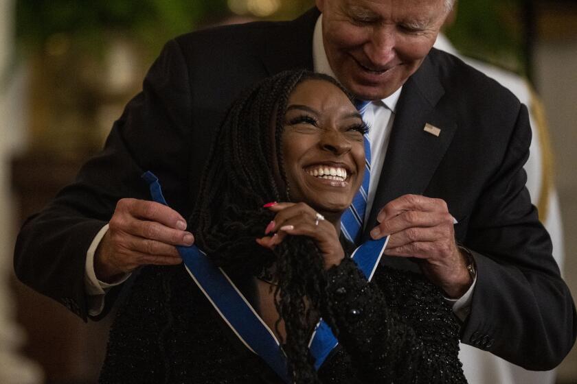 WASHINGTON, DC - JULY 07: President Joe Biden presents the Presidential Medal of Freedom to Simone Biles, Olympic gold medal gymnast and mental health advocate, during a ceremony in the East Room of the White House on Thursday, July 7, 2022 in Washington, DC. The nation's highest civilian award honors individuals who have made exemplary contributions to the prosperity, values, or security of the United States, world peace, and/or other significant societal, public or private endeavors. (Kent Nishimura / Los Angeles Times)
