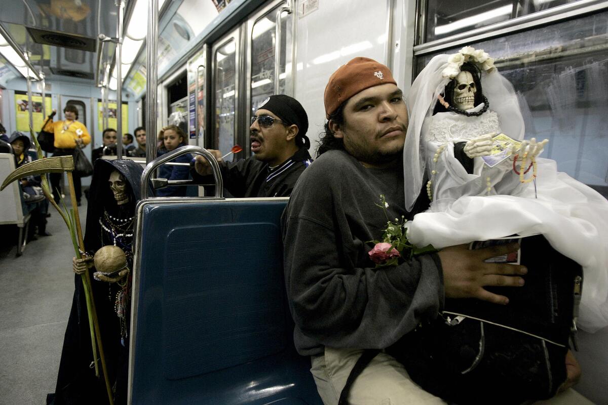 Men holding effigies ride the metro in Mexico City after a commemoration.