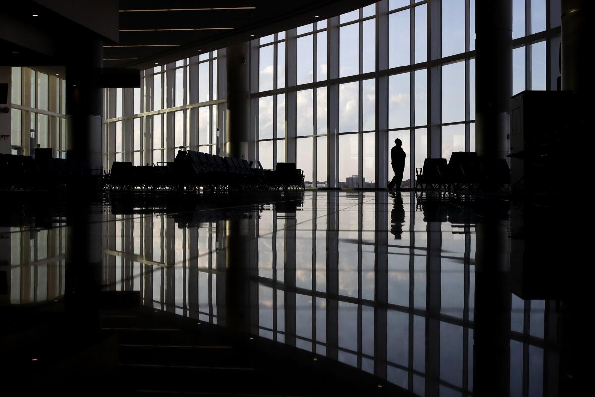 A woman looks through a window at a near-empty terminal at an airport in Atlanta. 