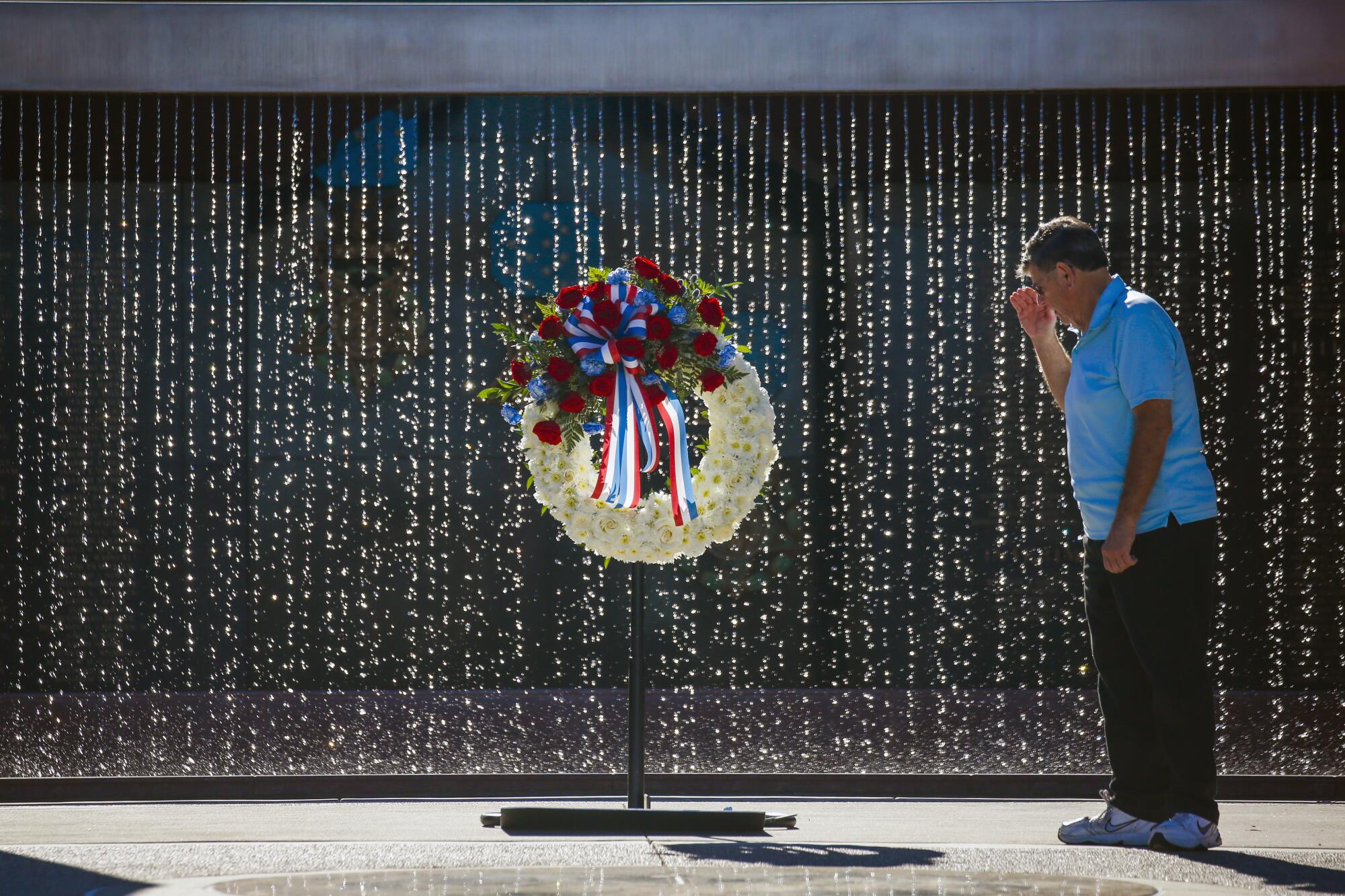 A man salutes in front of a wreath