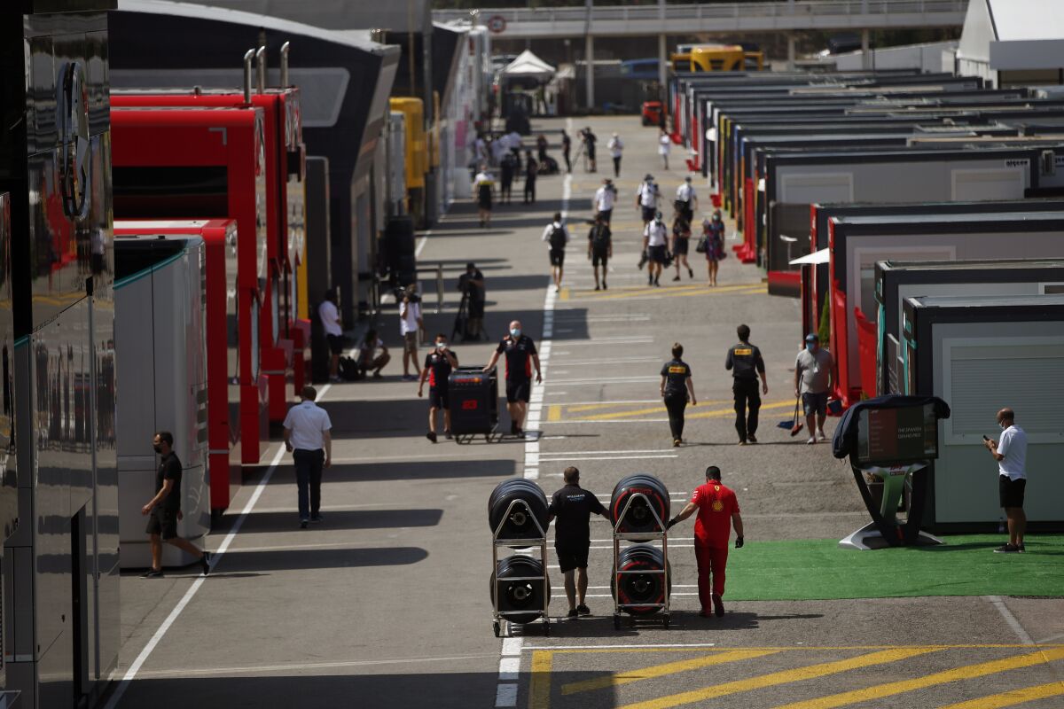 People walk through the paddocks before the Formula One Grand Prix at the Barcelona Catalunya racetrack in Montmelo, Spain, Thursday, Aug. 13, 2020. (AP Photo/Emilio Morenatti)