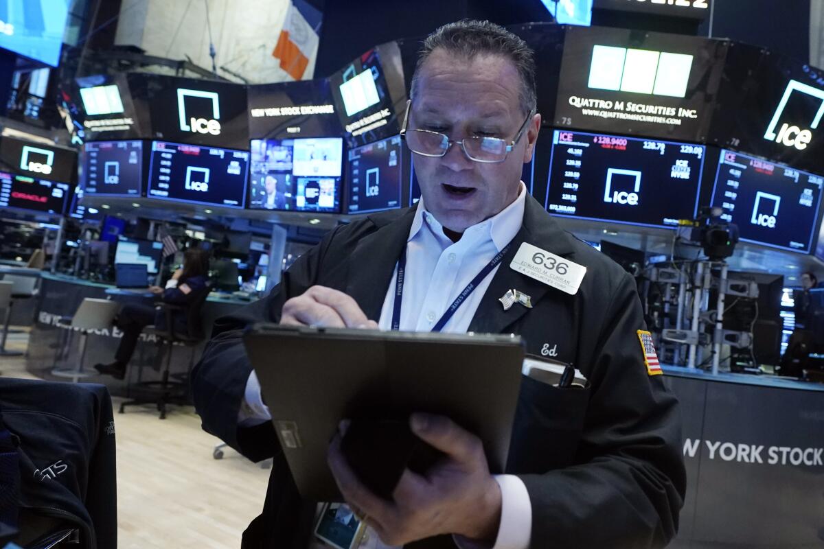 A man is looking at a computer tablet on the trading floor of the New York Stock Exchange.