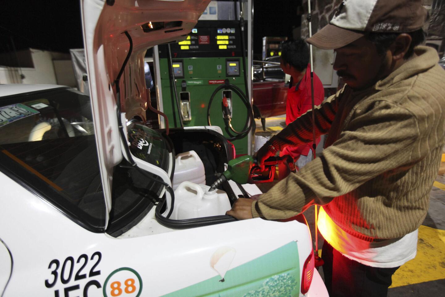 A taxi driver fills containers in his trunk with gasoline after waiting for hours at a fuel station in Valle de Bravo, Mexico.