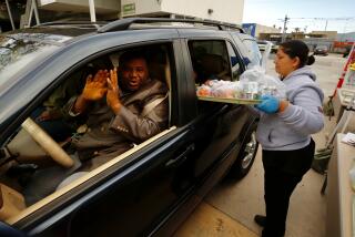 LOS ANGELES CA MARCH 18, 2020 -- Alake Ilegbameh said OMay God continue to bless youO over and over again as heOs driving his 3 school age children while he picks up food kits from LAUSD employee Benjula Prasad, right, being distributed to drivers in vehicles at Dorsey High School 3537 Farmdale Ave in Los Angeles Wednesday morning (Al Seib / Los Angeles Times)