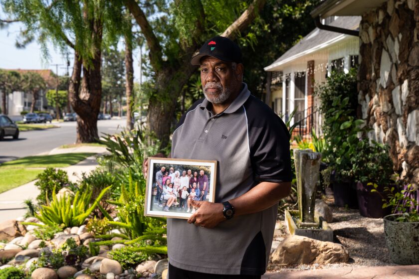 INGLEWOOD, CA - MAY 22: Holding a photo depicting members of his extended family, Tony Wafford poses for a portrait outside his home on Friday, May 22, 2020 in Inglewood, CA. Wafford, a healthcare educator at Oasis Clinic at Martin Luther King Jr. Community Hospital and his wife Diane Walker a retired Sheriff commander have lost relatives to COVID19 in a little more than a week. (Kent Nishimura / Los Angeles Times)