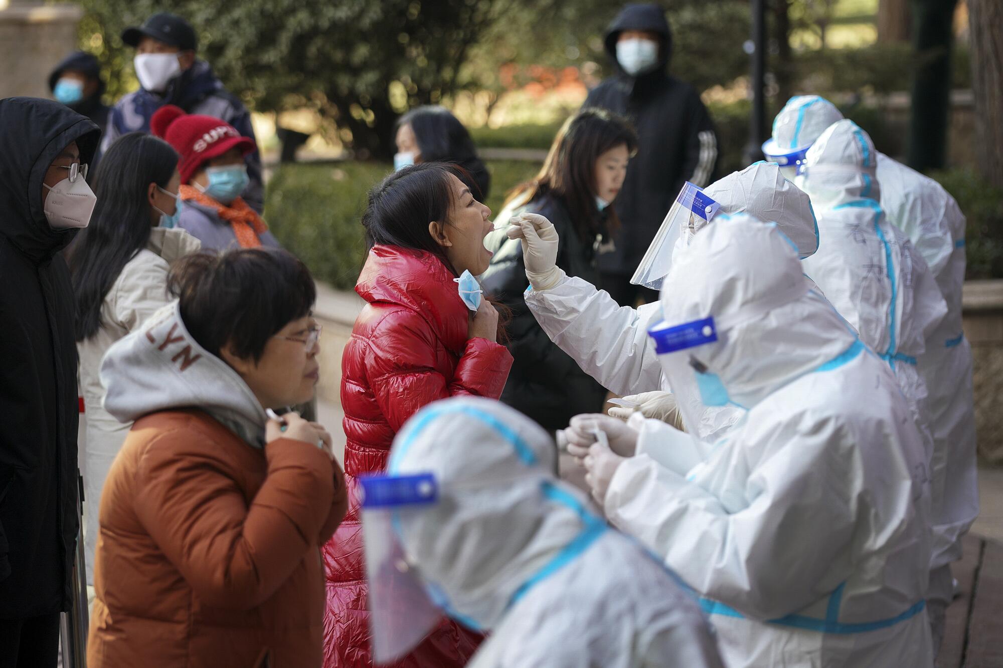 Medical workers in protective suits take swabs from residents in Shijiazhuang, China.