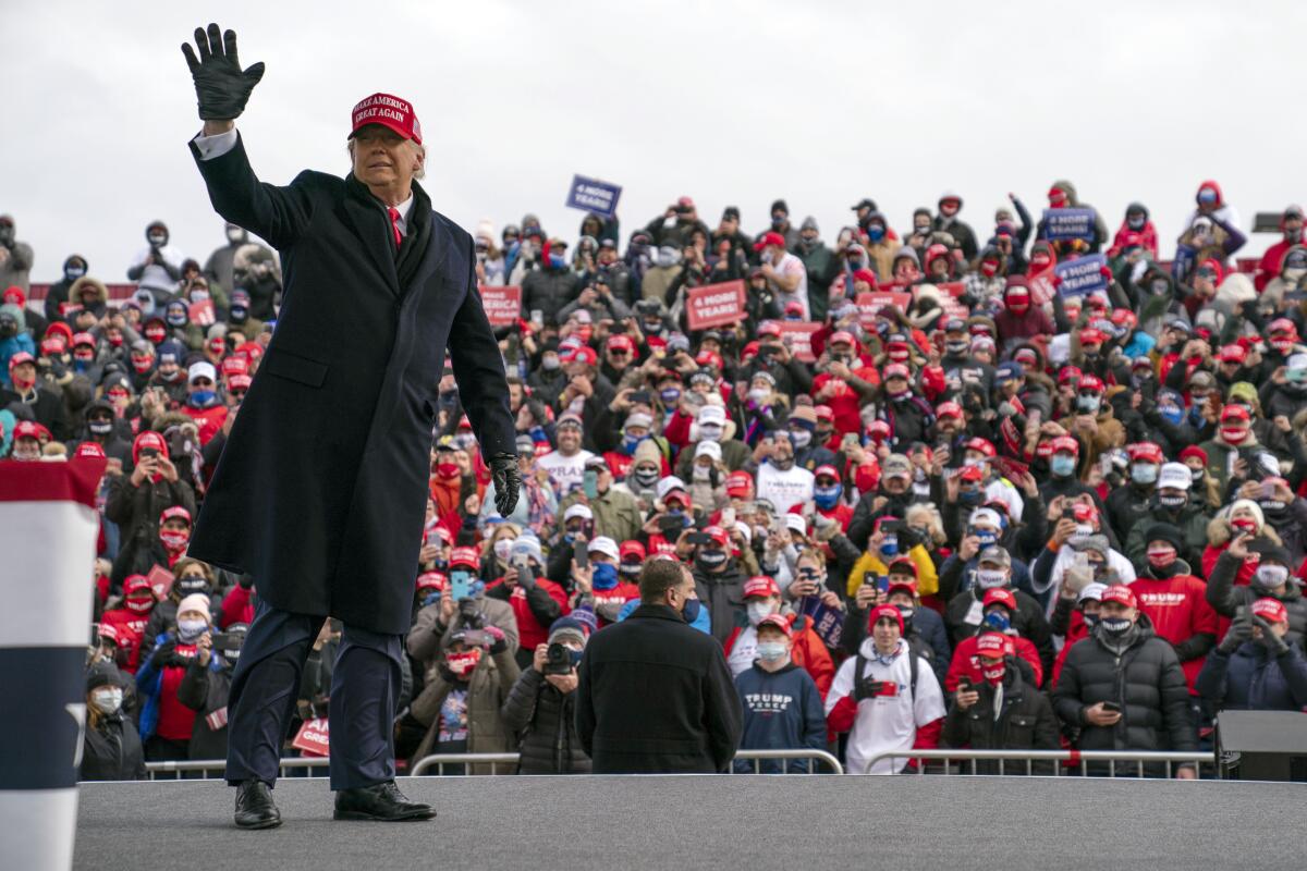 President Donald Trump waves as he walks off stage after speaking during a campaign rally at Michigan Sports Stars Park