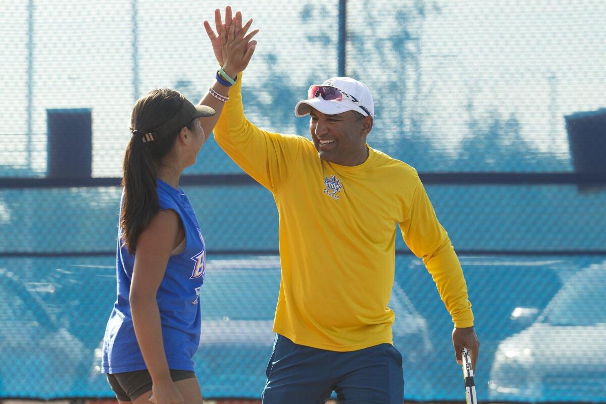 Fountain Valley High girls’ tennis head coach Harshul Patel high-fives senior captain Katie Ho during practice. The duo has helped the Barons rise to first place in the Sunset League this season.