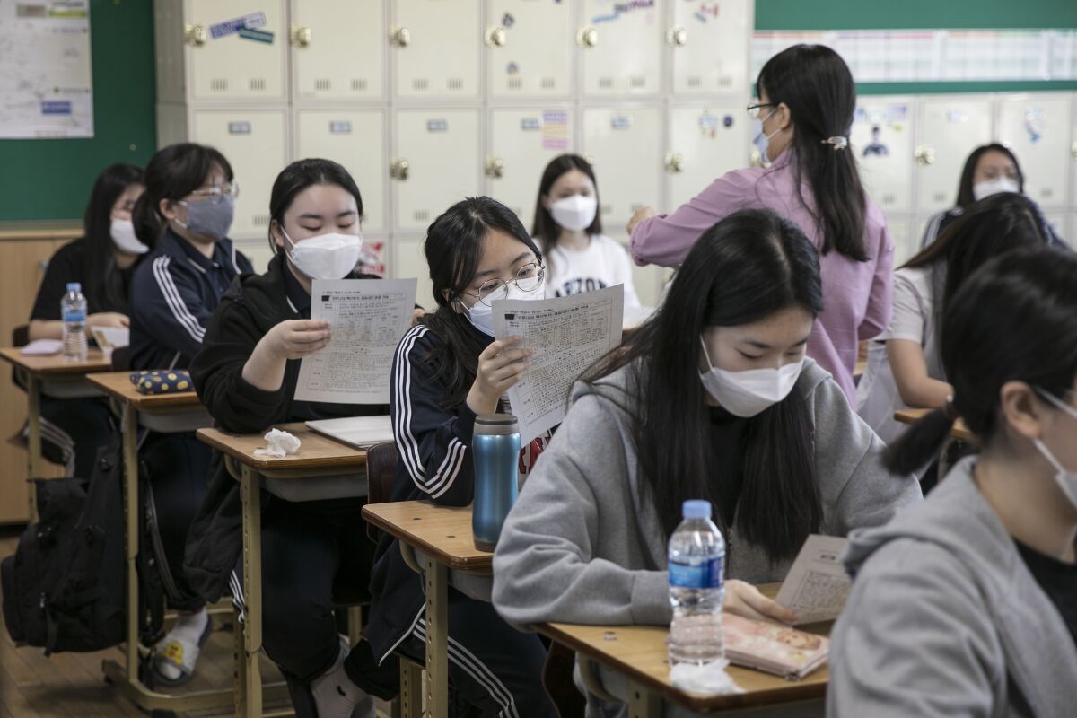 South Korean students in masks work at their desks.