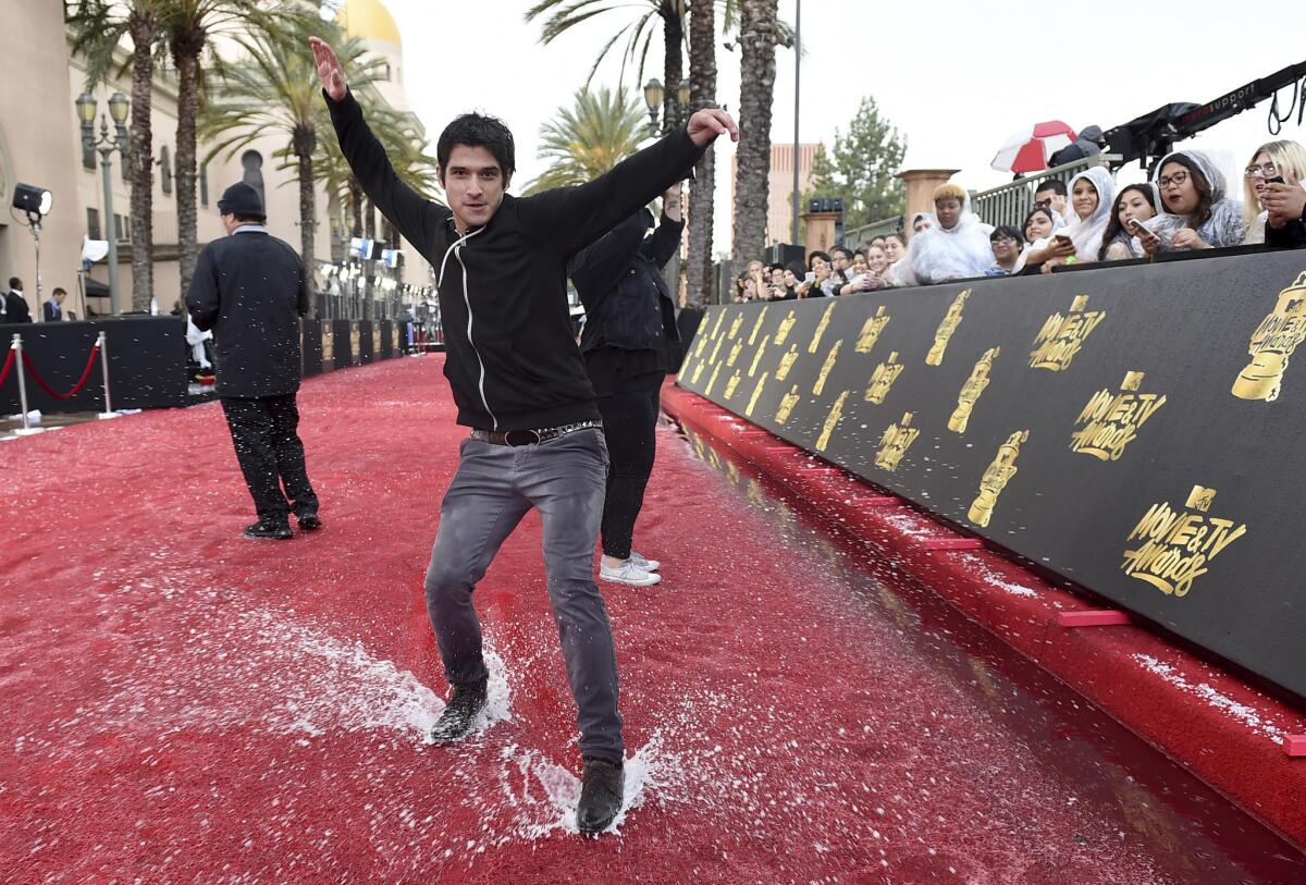 Actor Tyler Posey slides on a soaked red carpet.