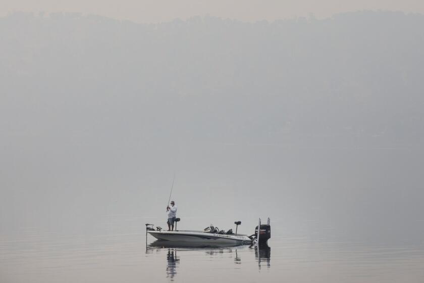 CLEARLAKE OAKS, CALIF. -- WEDNESDAY, AUGUST 8, 2018: A man is fishing in Clear Lake as the smoky haze shrouds visibility in Clearlake Oaks, Calif., on Aug. 8, 2018. (Marcus Yam / Los Angeles Times)