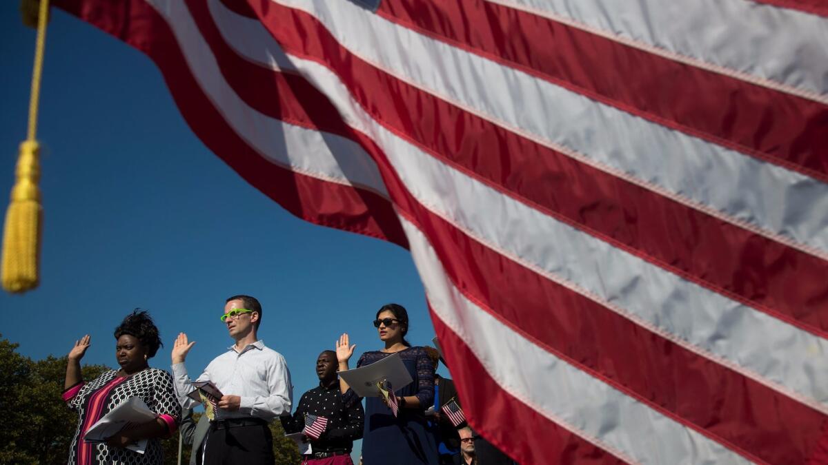 An American flag billows in the wind as immigrants stand and take the pledge of allegiance to the United States during a naturalization ceremony at Liberty State Park in Jersey City, New Jersey.
