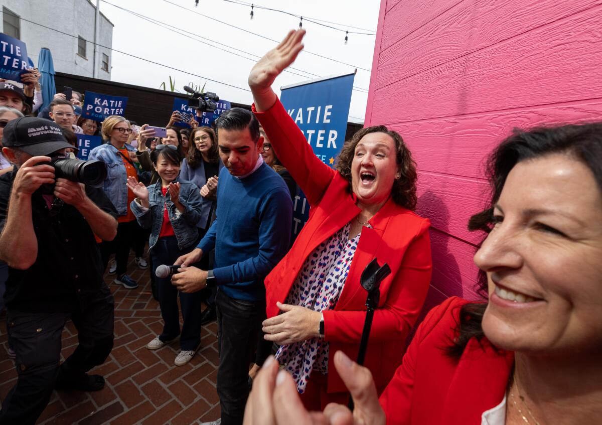 Rep. Katie Porter waves to supporters with Rep. Robert Garcia and Assemblywoman Cottie Petrie-Norris at a campaign event.