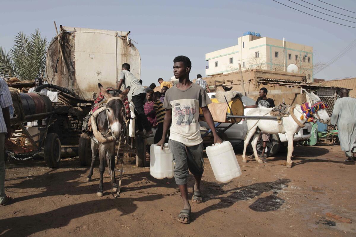 ARCHIVO - Varias personas se reúnen para recoger agua en Jartum, Sudán
