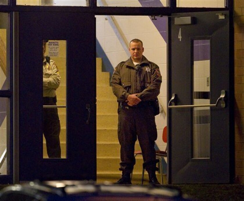 Law enforcement officials stand guard in the doorway of Marinette High School Tuesday morning Nov. 30, 2010 in Marinette, Wis. Authorities say a teen who held 24 hostages in a Wisconsin classroom has potentially life-threatening injuries from a self-inflicted gunshot wound. (AP Photo/Mike Roemer)