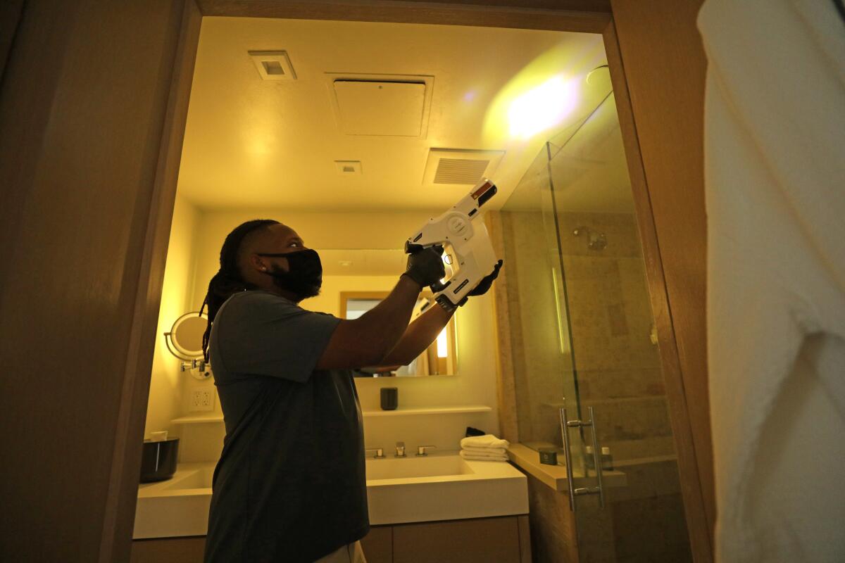 A Malibu Beach Inn employee shows how a room is disinfected. 