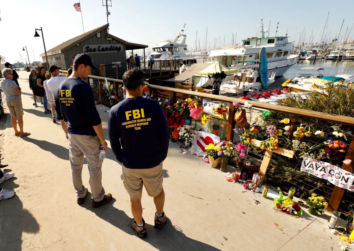 Members of an FBI dive team look at a growing memorial to the victims of the Labor Day fire aboard the Conception.