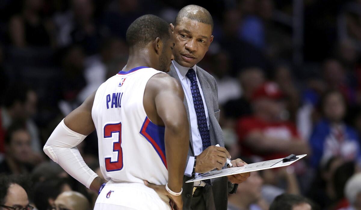 Point guard Chris Paul (3) goes over a play with Coach Doc Rivers.