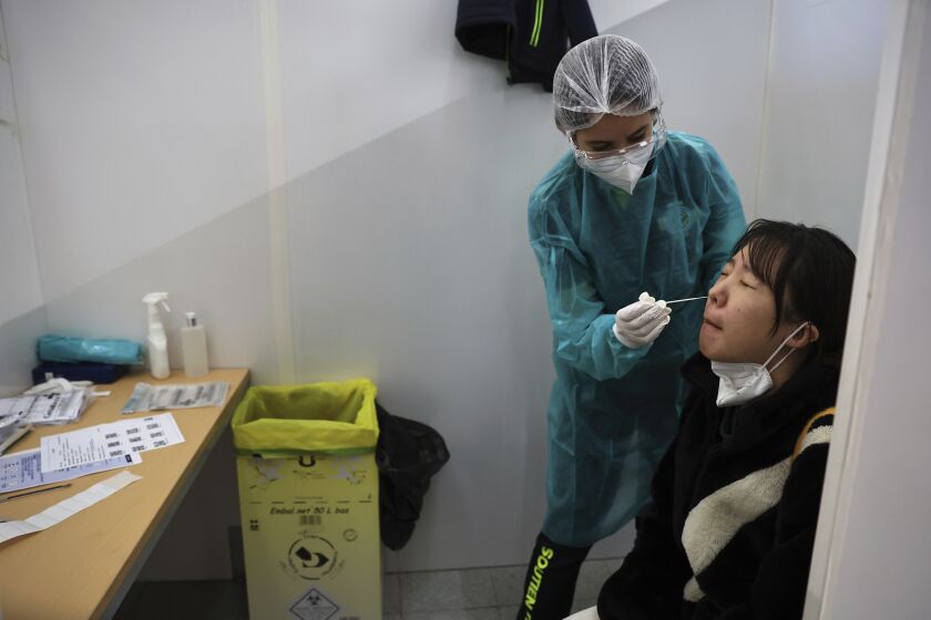 A passenger arriving from China is tested for COVID-19 at the Roissy Charles de Gaulle airport, north of Paris, Sunday, Jan. 1, 2023. France says it will require negative COVID-19 tests of all passengers arriving from China and is urging French citizens to avoid nonessential travel to China. (AP Photo/Aurelien Morissard)