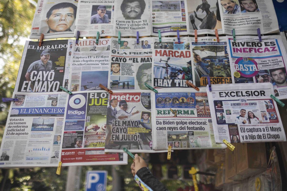 The front pages of more than a dozen Mexican newspapers displayed outside, held together by colored clothespins 