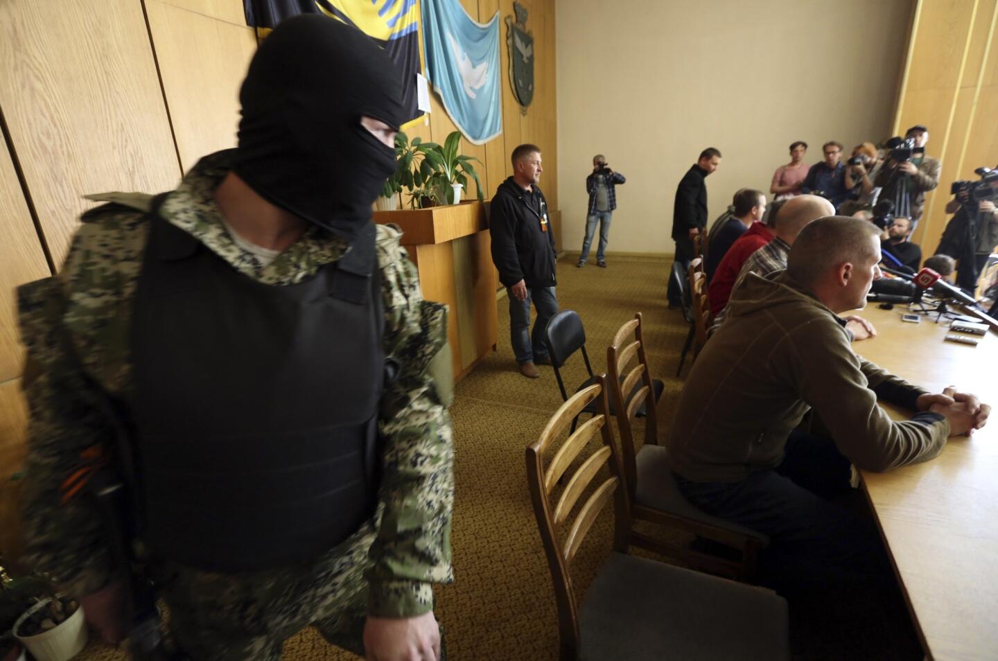 A pro-Russia gunman keeps watch before the start of a news conference with observers from the Organization for Security and Cooperation in Europe. Seven observers and one interpreter for the group were taken prisoner along with four Ukraine army officers last week outside Slovyansk during their inspection trip across southeastern Ukraine.