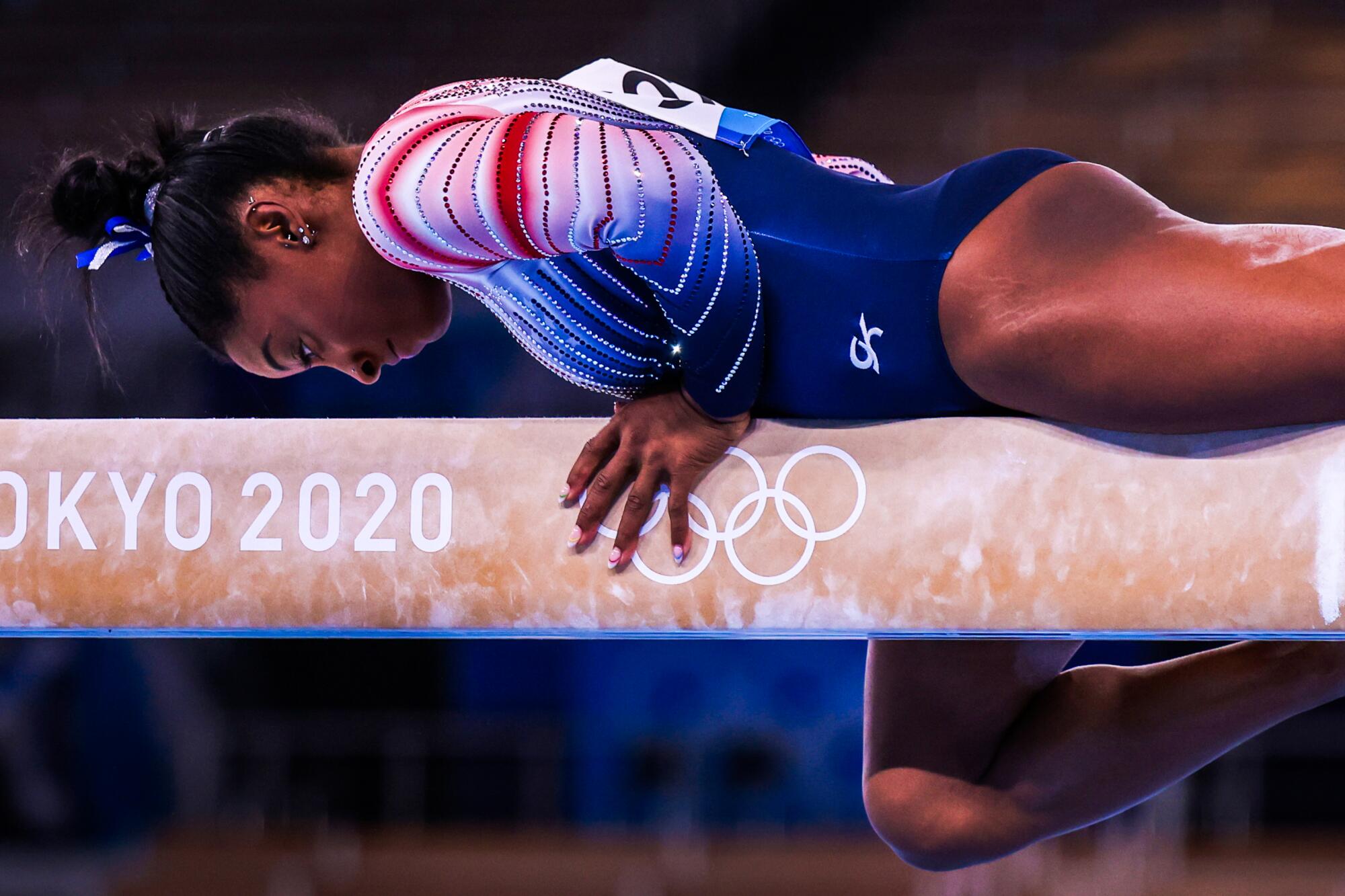 Simon Biles lies on the balance beam during her routine.