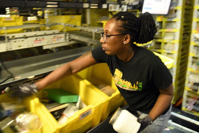 Jackie Spence places ordered products into bins in the Amazon's BWI2 fulfillment center on Broening Highway in Baltimore on May 20, 2019. (Jerry Jackson/Baltimore Sun/TNS) ** OUTS - ELSENT, FPG, TCN - OUTS **