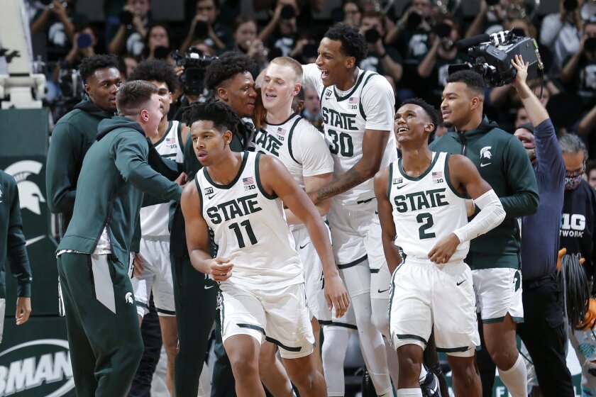 Michigan State players, including A.J. Hoggard (11), Marcus Bingham Jr. (30), Tyson Walker (2) and Joey Hauser, center, celebrate after defeating Minnesota in an NCAA college basketball game, Wednesday, Jan. 12, 2022, in East Lansing, Mich. Michigan State won 71-69. (AP Photo/Al Goldis)