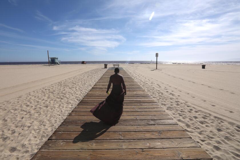 SANTA MONICA, CA - MAY 06, 2020 - - Majid Bradshaw, 33, makes his way down a walkway on a hot afternoon in Santa Monica on May 6, 2020. The beaches in Santa Monica were still closed but a few people still made their way to the beach and to the edge of the Pacific Ocean. (Genaro Molina / Los Angeles Times)