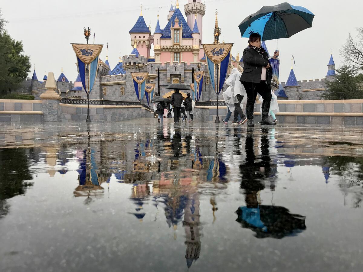 Disneyland guests walk past the Sleeping Beauty Castle while visiting Disneyland in Anaheim, Calif., on March 12, 2020