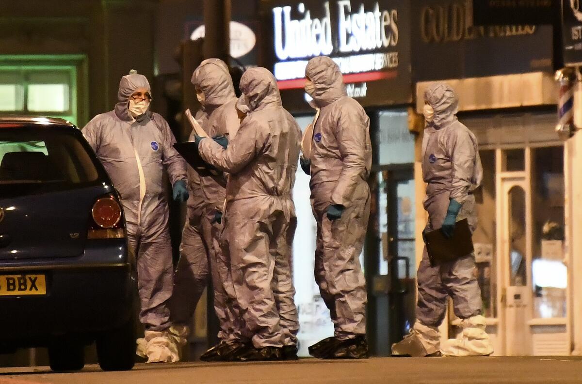 Police forensic officers work near the scene after a stabbing incident in Streatham London, England, Sunday, Feb. 2, 2020. London police officers shot and killed a suspect after at least two people were stabbed Sunday in what authorities are investigating as a terror attack.
