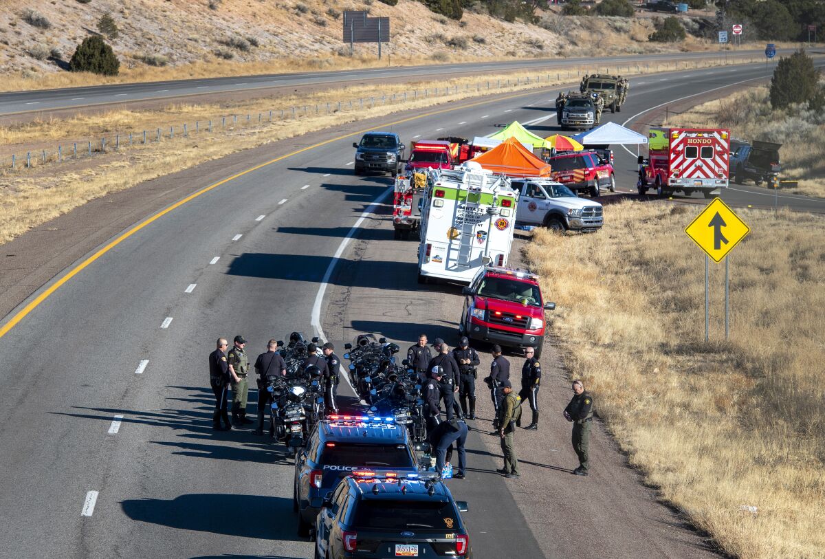 Law enforcement gathers along Interstate 25 as several agencies take part in a search for a suspect who was involved in a kidnaping and high speed chase that resulted in a Santa Fe Police Officer being killed, Wednesday March 2, 2022, near Santa Fe, N.M. (Eddie Moore/The Albuquerque Journal via AP)