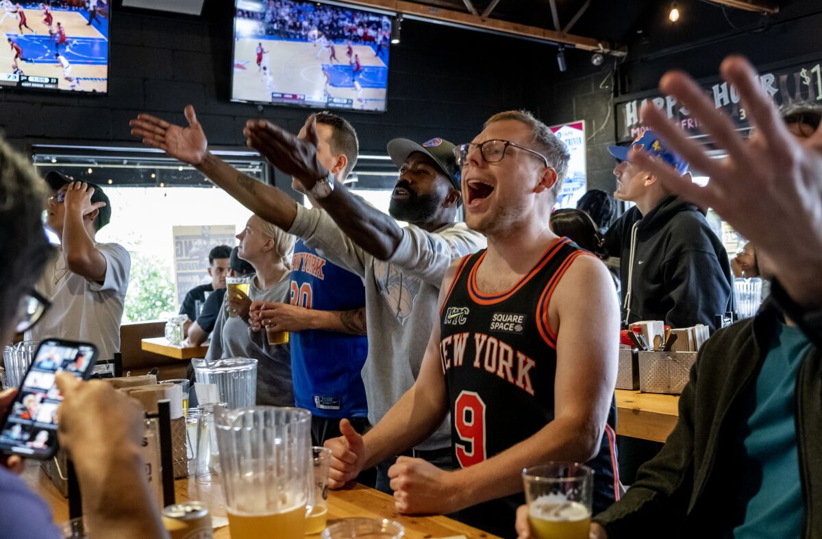 New York Knicks fans cheer while watching the team play on televisions displayed at 33 Taps bar in Los Angeles.