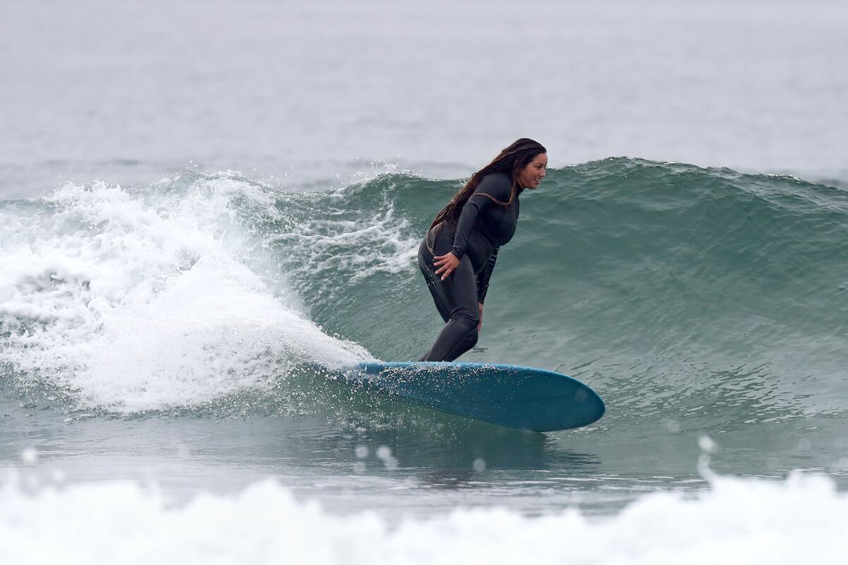 Costa Mesa resident Vanessa Yeager, 38, rides a wave along the north side of Newport Beach Pier.