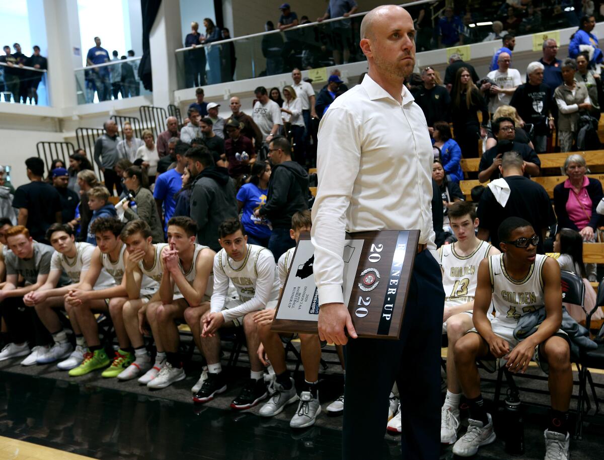 St. Francis High basketball coach Todd Wolfson holds the runner-up plaque after the Golden Knights lost to Santa Clarita Christian, 61-39, in the CIF Southern Section Division II-AA championship game Saturday.