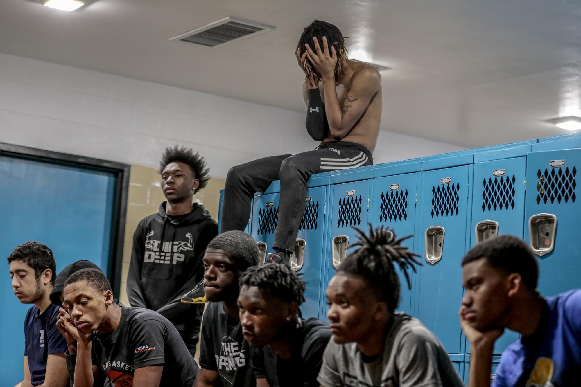 Taevion Rushing, sitting on the the lockers, and his Flint teammates listen to coach Demarkus Jackson.