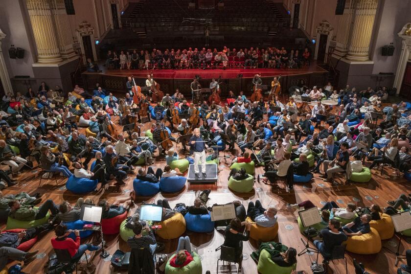 The Budapest Festival Orchestra, conducted by Ivan Fischer, perform Dvorak's Symphony No.8 in the Usher Hall at the Edinburgh International Festival, in Edinburgh, Tuesday, Aug. 8, 2023. Audience members were invited to sit on bean-bags in amongst the musicians as the concert was one of a number of new ways of presenting classical music at the festival this year. (Jane Barlow/PA via AP)
