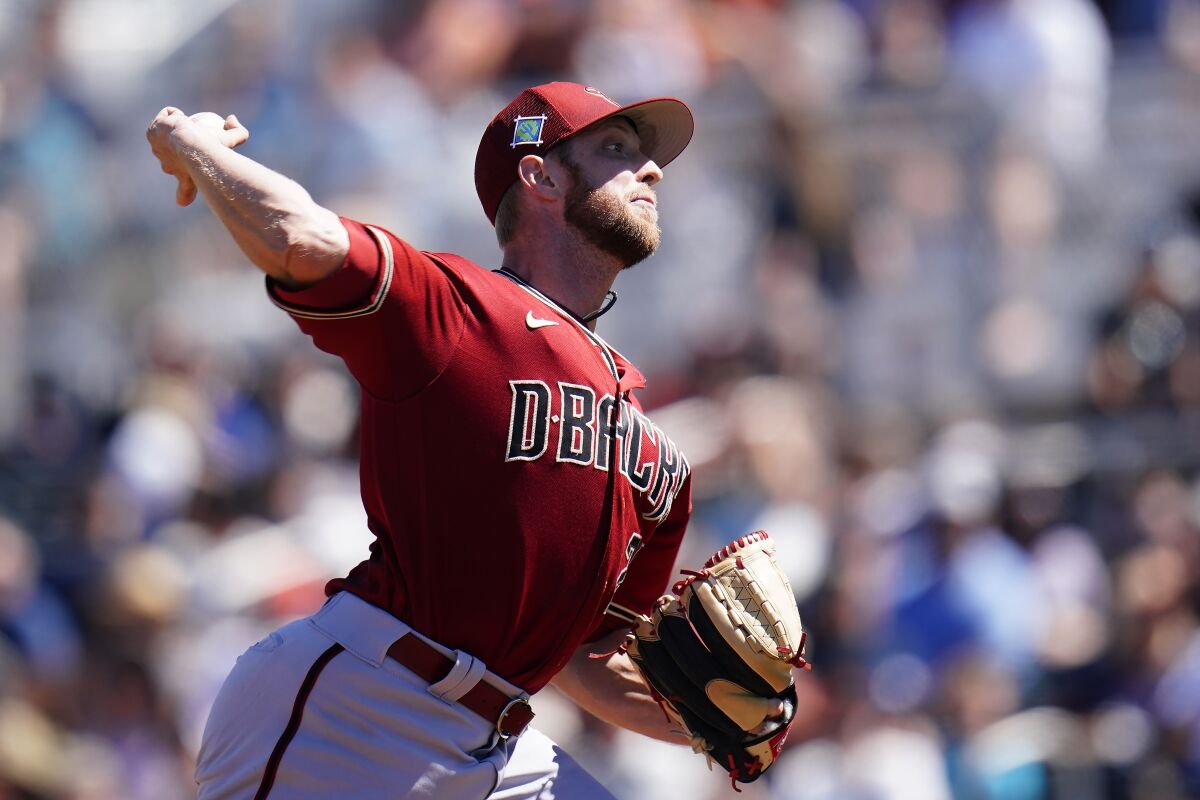 Arizona Diamondbacks starting pitcher Merrill Kelly throws a pitch against the San Francisco Giants during the first inning of a spring training baseball game Wednesday, March 23, 2022, in Scottsdale, Ariz. (AP Photo/Ross D. Franklin)